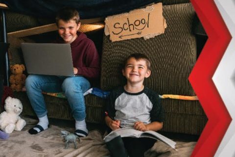 One kid drawing on the book and other kids looking at the laptop at the home