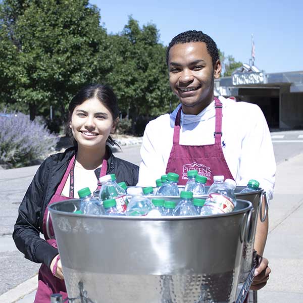 two students carrying buckets of bottle water