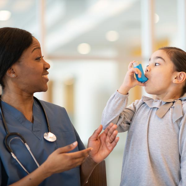 nurse teaching young girl to use inhaler